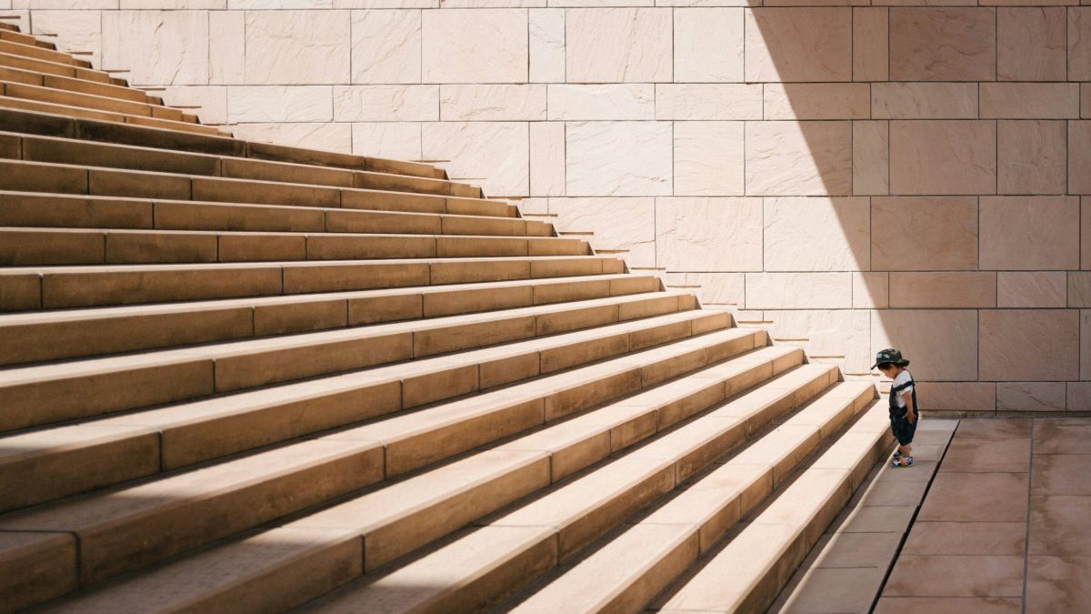 Kleines Kind vor grosser Treppe, symbolisch für große Aufgaben.